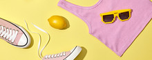 Fashion Accessories Minimal Flat Lay. Trendy Shoes Sneakers, Sunglasses, Lemon. Pop Art Pink Concept. Woman Fashionable Accessories On Yellow, Top View, Banner. Creative Design Color