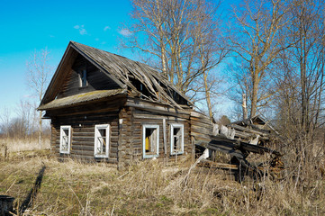 abandoned old house in a Russian village on a Sunny day, dry grass around the house, early spring