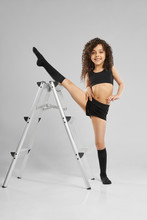 Little Female Gymnast Demonstrating Split Near Ladder.
