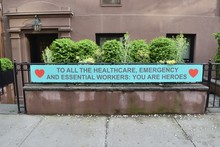 Sign On A Fence Railing Reading To All The Healthcare, Emergency And Essential Workers: You Are Heroes With Two Red Heart Symbols And A Brownstone And Green Shrubs, May 1, 2020, In New York.