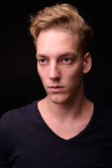 Face of young blond Scandinavian man thinking against black background