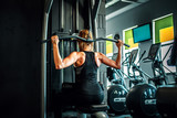 Kobieta trenująca na siłowni, mięśnie pleców. 