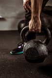 Dłonie trzymające kettlebell, sportowiec uprawiający crossfit, podnoszenie ciężarów.