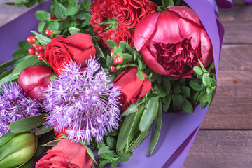 bouquet with red flowers in purple packaging on a wooden background. high quality