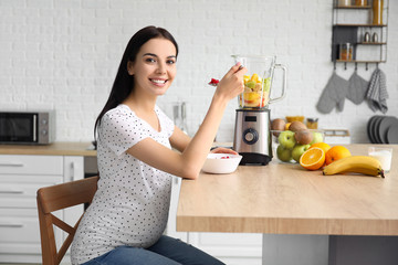 Sticker - Young pregnant woman making fruit smoothie in kitchen at home