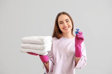 Poster - Beautiful young woman with clean towels and detergent on grey background