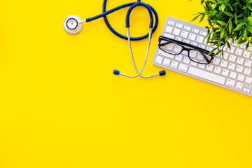 Stethoscope on doctor office desk. Yellow background top view space for text