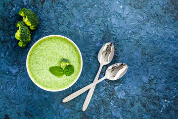 Wall Mural - Broccoli soup puree on blue kitchen table top view copy space