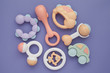 Flat lay composition with baby rattles set in pastel colors on lilac background.