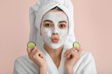 Poster - Beautiful young woman with cucumber slices and facial mask on color background