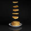 Pancakes falling onto stack of pancakes on plate, isolated on dark background