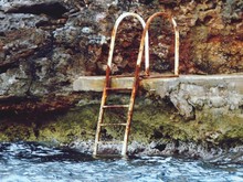 Close-up Of Iron Ladder And Water Against Rocky Wall