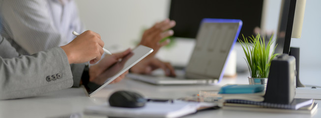 Side view of businesspeople working together with tablet, laptop, office supplies