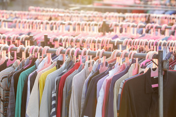 Huge selection of different used clothes for men, women and children on the rack in a second hand shop or thrift store. Concept of waste problem in fashion industry.