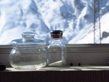Close-up Of Glass Jars On Window Sill Against Snowcapped Mountain