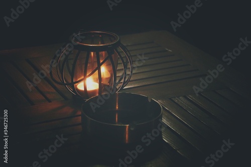 Cuadros en Lienzo High Angle View Of Illuminated Lantern By Ashtray On Table In Darkroom