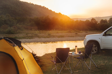 Wall Mural - camping at beach of mountain river. suv car. yellow tent. camp table and chairs
