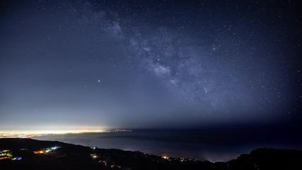 Wall Mural - time lapse of the starry night sky and the milky way rising over the glowing lights of los angles
