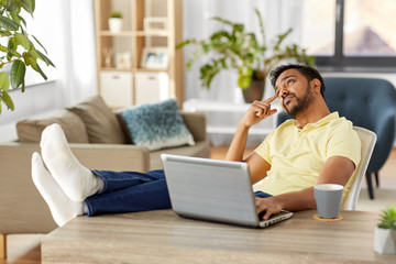 Sticker - technology, remote job and lifestyle concept - indian man with laptop computer resting feet on table and thinking at home office