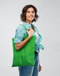 © Syda Productions - people concept - portrait of happy smiling young woman in turquoise shirt with green reusable canvas bag for food shopping on grey background