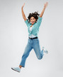 © Syda Productions - people, ethnicity and portrait concept - happy young woman in turquoise shirt and jeans jumping with hands up over grey background