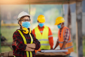 Asian woman civil engineer paper plan building architect wearing white safety helmet look at contruction site.Female foreman in a construction helmet, facemask,