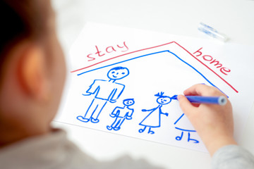 Wall Mural - Child is drawing family with words Stay Home on white sheet of paper at home. Children's creativity in quarantine.