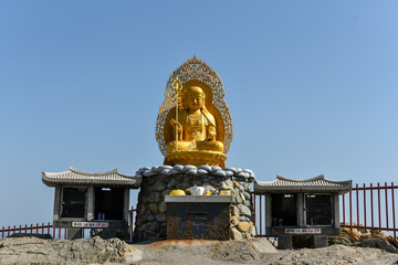 Wall Mural - Busan city, South Korea - NOV 01, 2019: Chinese culture golden Buddha sculpture that standing on the respective shrine near Haedong Yonggung Temple.