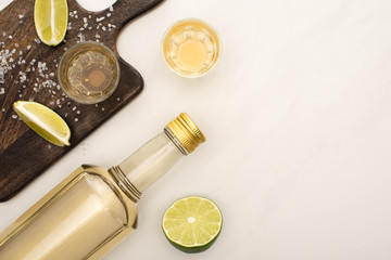 Wall Mural - top view of golden tequila with lime, salt on wooden cutting board on white marble surface