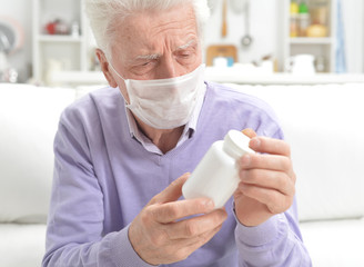 Poster - Portrait of sad sick senior man with facial mask holding pills