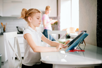 Pretty stylish schoolgirl studying homework math during her online lesson at home, social distance during quarantine, self-isolation, online education concept, home schooler