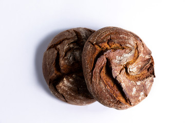 Two round loaves of rye bread on white background.