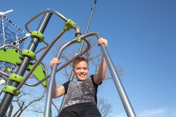 Cheerful teenager swinging on a swing in the park at the playground. Child on a summer walk