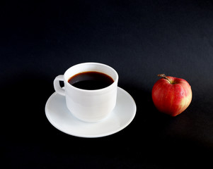 A Cup of black coffee and a red Apple on a black table. Suitable for mockups and advertising backgrounds