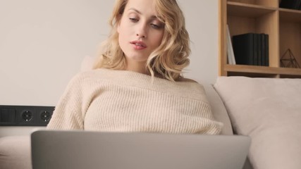 Canvas Print - Young tired yawning blonde woman indoors at home using laptop computer