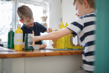 Wall Mural - Brothers painting a cardboard dinosaur costume