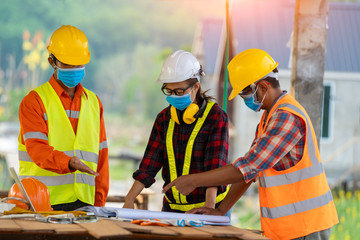 Wall Mural - Engineer wearing protective mask to Protect Against Covid-19 working at construction site,Architect Engineer Meeting People Brainstorming Concept.