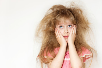 Wall Mural - a little girl with tangled long hair in a pink dress on a white background tries to comb it. naughty