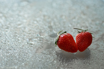 two strawberries on a glass table