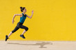 © Westend61 - Young woman jogging in front of a yellow wall