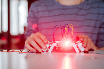 Boy's hand assembling robot, red light
