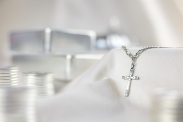 Still life photo of a silver cross and silver bars