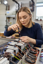 Female Electrician Working On Circuitry In Workshop