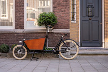 Typical Dutch Carrier Bicycle Parked In Front Of A House. Modern Urban Parents Use These Carrier Bikes To Transport Their Children Or Groceries