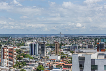 View from a height overlooking the city of Manaus in the state of Amazonas, with a cloudy sky overhead and tall urban buildings down below in Brazil, South America