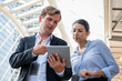 © Nopphon - Portrait of businessman and woman using tablet while standing on urban city background