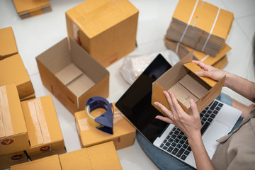 Female business owner working, packing the order for shipping to customer. Female entrepreneur packaging box for delivery.