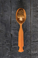 Wall Mural - Wooden spoon with a Morel on a wooden background.