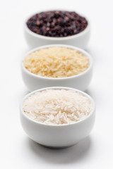 Rice grain types foreground focus. 3 varieties of rice with focus on the white jasmin rice while the basmati and black rice behind are blurred. Rice is the most consumed staple food ingredient.