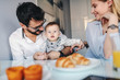© Dusan Petkovic - Young happy parents sitting in dining room with their adorable baby boy. Man holding baby. On table is breakfast.
